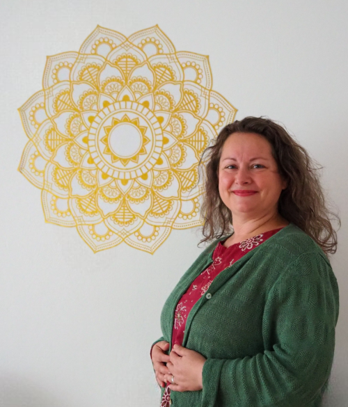 Manuela Pieper-Meißner steht vor einer Wand mit einem Mandala Wand Tattoo